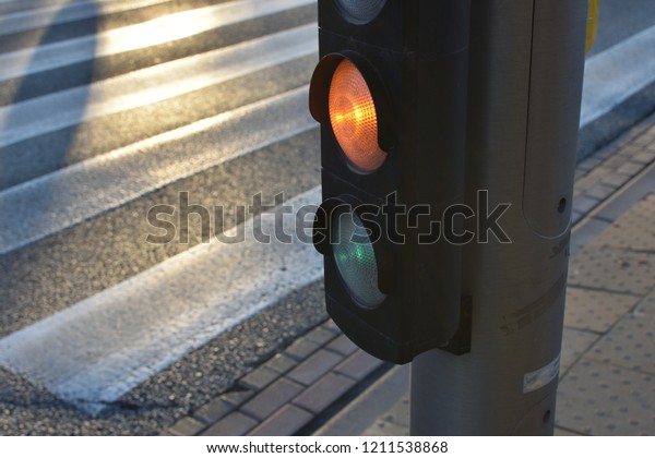 Yellow traffic light for cars and crosswalk in\
sunset twilight, closeup