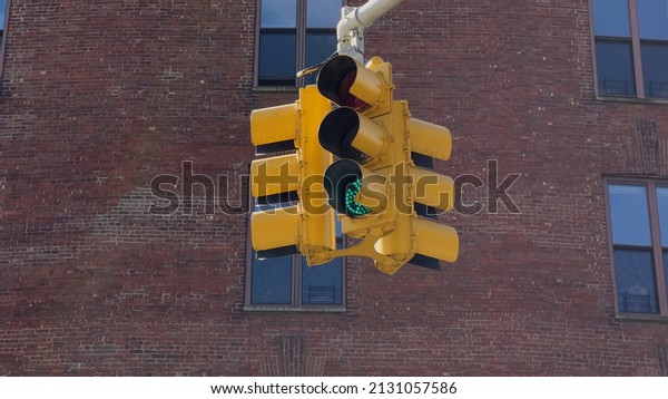 A yellow traffic light hangs at an\
intersection in New York, USA. Red stop signal. Traffic management\
on the road. Transport in the city.\
Stoplight.