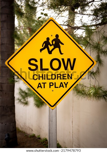 Yellow traffic sign with graphic stating Slow\
Children at Play