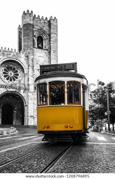 Yellow\
tram against the Lisbon Cathedral in Alfama district of Lisbon,\
Portugal. Black and white photo with coloured\
tram