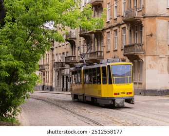 A yellow tram passes on a cobblestone street in Lviv with old European architecture. The inscription on the tram: «Body overhang 1.7 meters» - Powered by Shutterstock