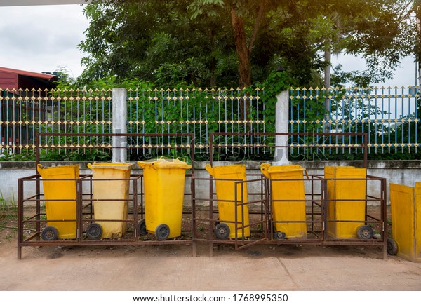 Yellow trash\
can is placed on the side of the\
road.
