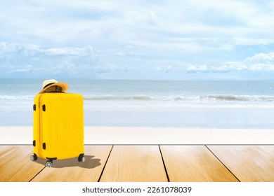 Yellow travel luggage with hat on wood surface. Beach sea on summer sunlight  blur background. - Shutterstock ID 2261078039