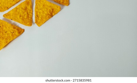 Yellow Triangular Tortilla Chips in Corner Arrangement on White Background with Copy Space