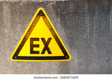 A yellow triangular warning sign with a black border and the letters 