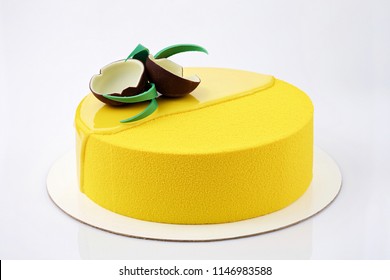 Yellow Tropical Mousse Cake Decorated With Coconut Of Chocolate On A White Background Closeup View