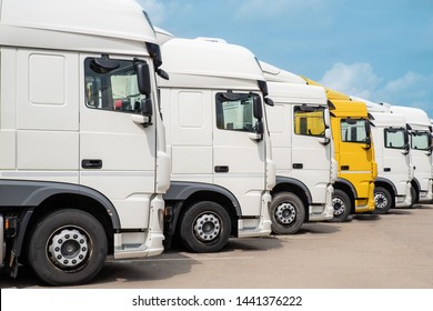 Yellow Truck Among White Trucks Lined Up Side View