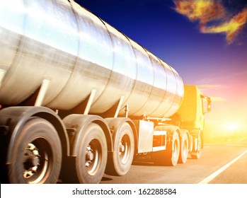 Yellow Truck On Blurry Asphalt Road Under Blue Sky And Sunset Light