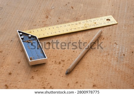 Yellow try square ruler and carpenter pencil on wooden board with sawdust. Woodworking measurement tools, carpentry workshop background, DIY home renovation or construction concept