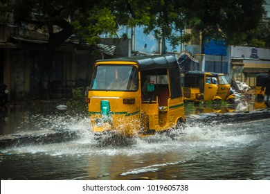 A Yellow Tuk-tuk Or Rickshaw In Chennai, India, Is Driving Around On The Flooded Streets. Water Splashing From The Wheels On A Tuktuk During Heavy Rain, Cyclone Or Monsoon. 