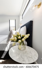 Yellow Tulips On A Marble Bedside Table With Gold Wall Light Above