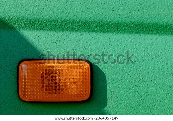 yellow turn signal on green car background,\
shadow makes triangle