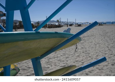 Yellow and turquoise surboard on a rack on a beach in Baja, California, Mexico.