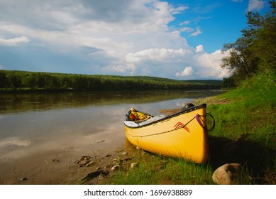 A Yellow Two Man Canoe On A Rivers Edge On A Summers Day In Alberta