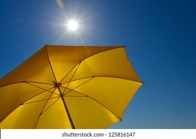 Yellow Umbrella With Bright Sun And Blue Sky