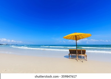 Yellow umbrella and wooden chairs on Hua Hin beach, Thailand