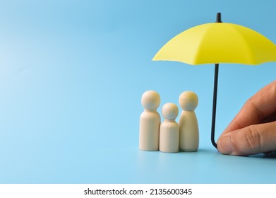 Yellow umbrella and wooden doll figures. Insurance coverage concept - Shutterstock ID 2135600345