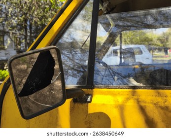 A yellow van with a broken mirror. The reflection of a white car