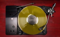 Yellow Vinyl Record Played On A Hi-end Turntable Record Player Top View Standing On Red Wood Stand