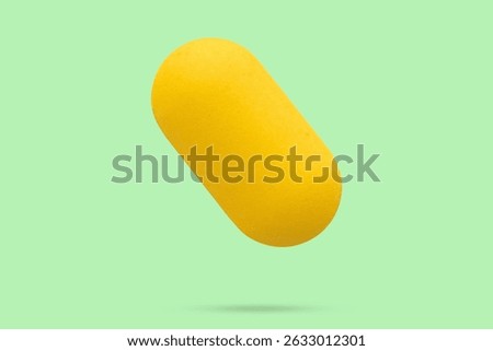 Yellow vitamin pill tablet float on green background