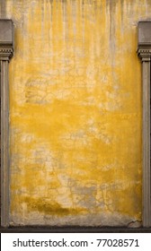 A yellow wall on an old building in Italy.  There are interesting variations in the paint and stonework, and posts from large windows on the sides.  Lots of room for copy.