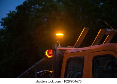 Yellow Warning Lights On Dump Truck. Road Construction Workers Repairing Highway Road On Late Night. Loaders And Trucks On Newly Made Asphalt. Heavy Machinery Working On Street.