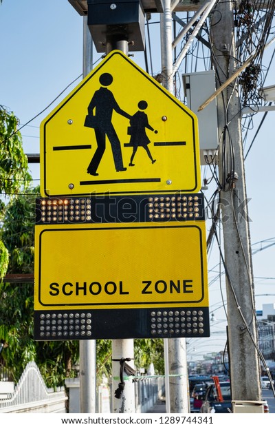 Yellow\
warning school zone sign with many dots of\
light.