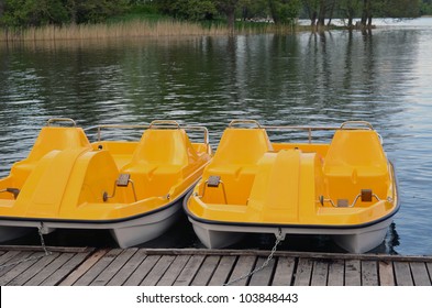 Yellow water bicycles locked at lake marina. Active recreation objects.
