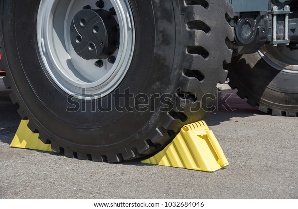 Yellow\
wheel chocks under the big black truck\
wheels