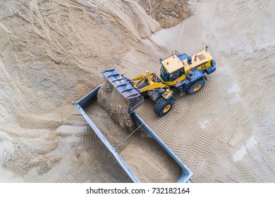 Yellow Wheel Loader Loading Sand On Dumper Truck. Sand Quarry