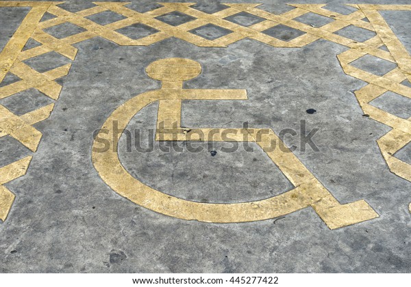 Yellow wheelchair Handicap Sign on dark\
asphalt and concrete road street\
background.