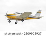 Yellow and white general aviation aircraft in flight. Single engine propellor driven piston airplane on departure. Low wings and fixed landing gear