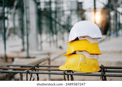 Yellow and white helmets for worker and supervisor stack on the Steel frame in factory construction site, contractor, real estate business, safety first concept.