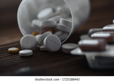 Yellow and white pills scattered from the jar. Nearby are pills in a bister. The concept of epidemic and protection against virus. - Shutterstock ID 1725188443