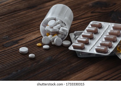 Yellow and white pills scattered from the jar. Nearby are pills in a bister.  - Shutterstock ID 1733330315