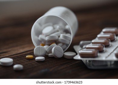 Yellow and white pills scattered from the jar. Nearby are pills in a bister. The concept of epidemic and protection against virus. - Shutterstock ID 1739463623