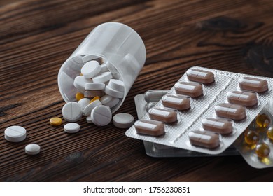 Yellow and white pills scattered from the jar on a wooden background. Nearby are pills in a bister.  - Shutterstock ID 1756230851
