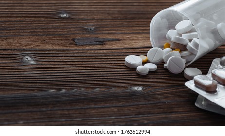 Yellow and white pills scattered from the jar. Nearby are pills in a bister. Copy space - Shutterstock ID 1762612994