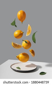 Yellow whole and sliced lemons levitate over plate. Isometric view minimal still life. Trending colors of 2021 - Shutterstock ID 1880448739