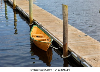 A yellow wooden boat docking at Perkins Cove on a Sunny Day, Ogunquit, Maine. 