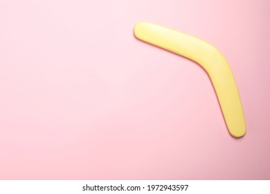 Yellow Wooden Boomerang On Pink Background, Top View. Space For Text