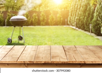 yellow wooden desk space and black grill in garden 