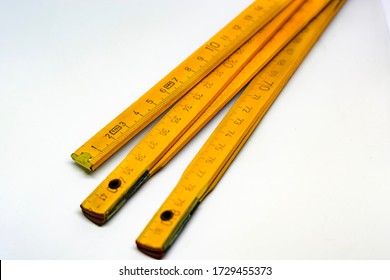 Yellow Wooden Folding Meterstick With Brass Ends Isolated On A White Background. Fully Extended It Measures 2 Meters. Measuring Instrument Used In Construction Industry