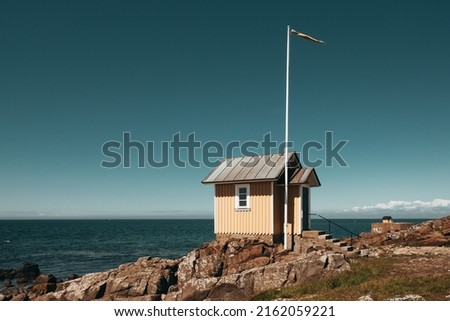 Yellow wooden hut on rocky coast in the seaside village of Torekov in Sweden.