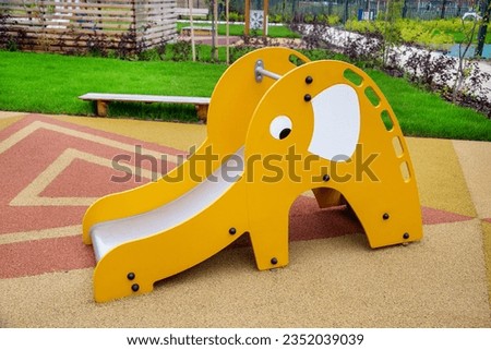 A yellow wooden slide in the form of an elephant on the playground in kindergarten on a clear sunny day. Playgrounds, toys, sports.