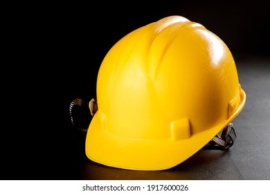 Yellow work helmet on a dark table. Protective accessories for construction workers. Dark background.