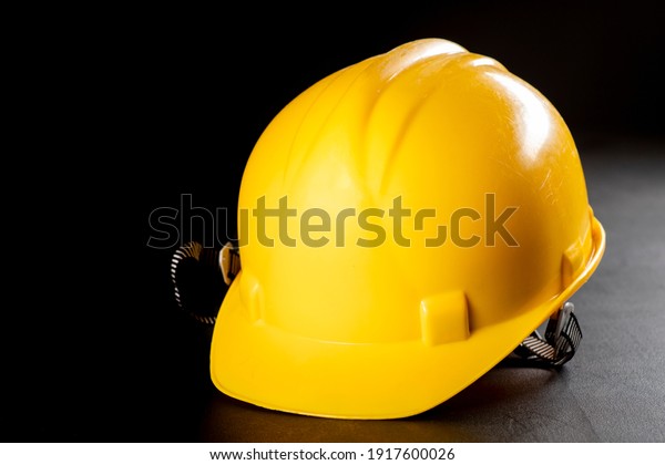 Yellow work helmet\
on a dark table. Protective accessories for construction workers.\
Dark background.
