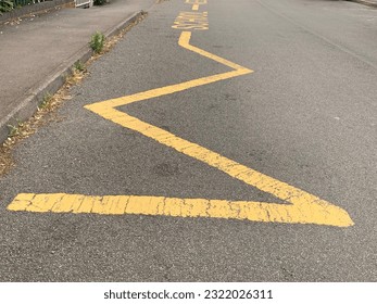 Yellow Zig Zag lines indicating to motorists to keep clear no parking taken outside school entrance UK - Shutterstock ID 2322026311