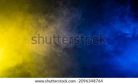 Yellow-blue smoke in neon light on black background.