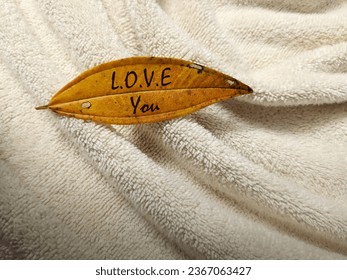 Yellowish leaf on white towel. Minimalist background with warm hue color theme. - Shutterstock ID 2367063427